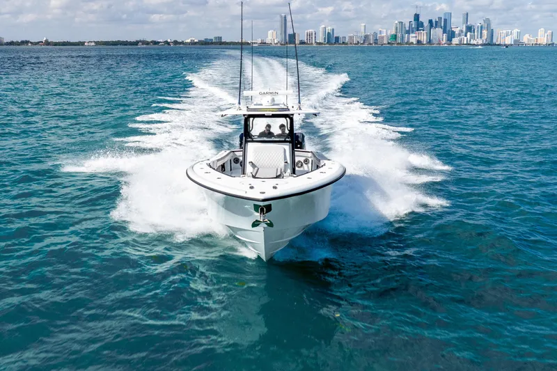 Slide: The Image of 2024 Yellowfin 39 Offshore boat cruising on blue ocean with city skyline in background. - 11