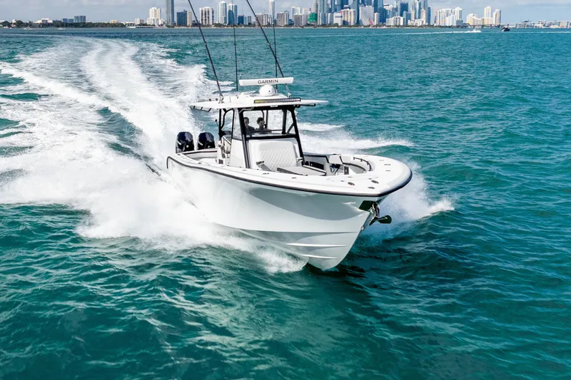 Slide: The Image of 2024 Yellowfin 39 Offshore boat cruising on blue ocean with city skyline in background. - 12