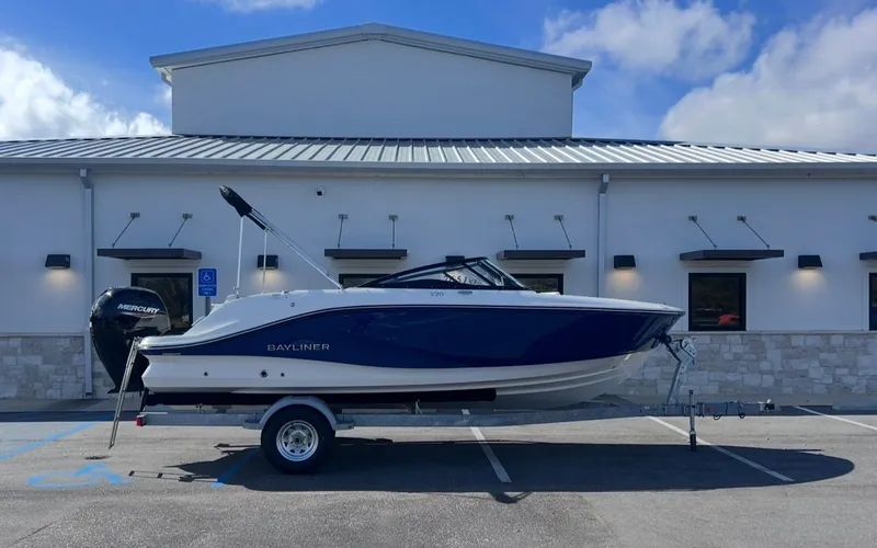 The Image of Bayliner V20 2026 boat on trailer in front of building. - 1