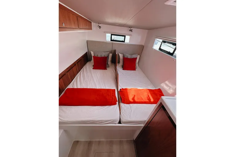 Slide: The Image of Modern cabin interior with twin beds, red accents, and wooden cabinetry in a 2022 Balance 526. - 18