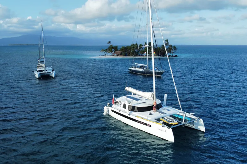 Slide: The Image of Sailboats near tropical island, featuring 2022 Balance 526 catamaran on clear blue ocean. - 5