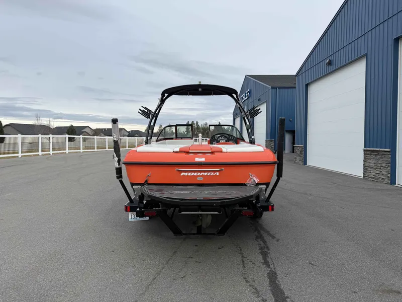 Slide: The Image of Rear view of orange 2015 Moomba Outback V boat in front of blue building. - 6
