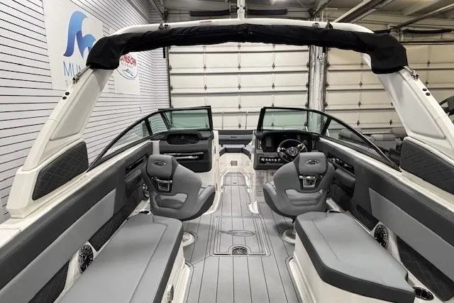 Slide: The Image of 2026 Chaparral SSX 8 boat interior with sleek seating and modern dashboard in a showroom. - 28