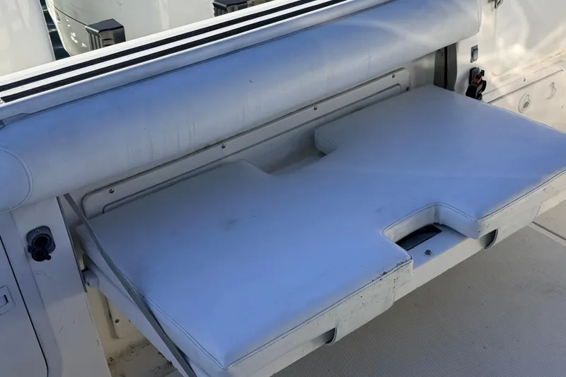 Slide: The Image of Wellcraft 270 Coastal O/B 2000 boat seat, white upholstery, folded down, marine setting. - 10