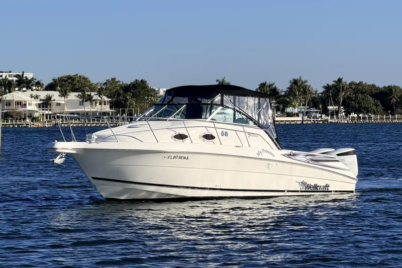 Slide: The Image of 2000 Wellcraft 270 Coastal O/B boat on water, clear sky, waterfront homes in background. - 3