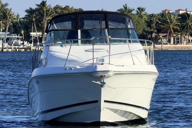 Slide: The Image of 2000 Wellcraft 270 Coastal O/B boat on water, surrounded by palm trees and waterfront homes. - 5