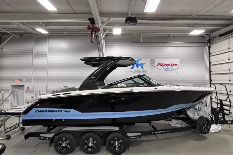 The Image of 2026 Chaparral SSX 30 boat in showroom, black and blue design, on trailer. - 0