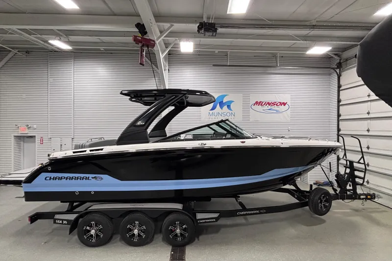 Slide: The Image of 2026 Chaparral SSX 30 boat in showroom, black and blue design on trailer. - 16