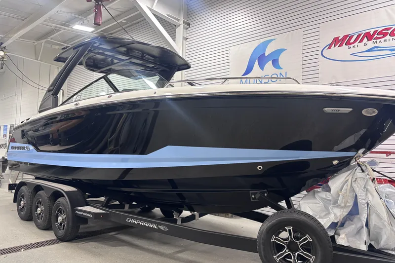 Slide: The Image of 2026 Chaparral SSX 30 boat on trailer in showroom, sleek black and blue design. - 5