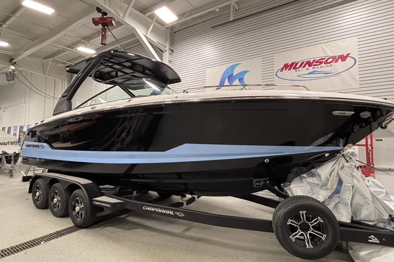 Slide: The Image of 2026 Chaparral SSX 30 boat on trailer in showroom, featuring sleek black and blue design. - 9