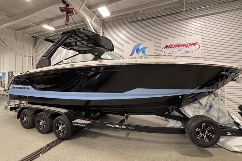 Slide: The Image of 2026 Chaparral SSX 30 boat on trailer in showroom, black and blue design. - 10