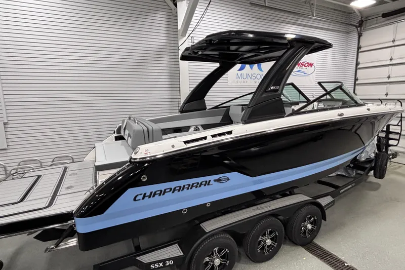 Slide: The Image of 2026 Chaparral SSX 30 boat in showroom, black and blue design, on trailer. - 13