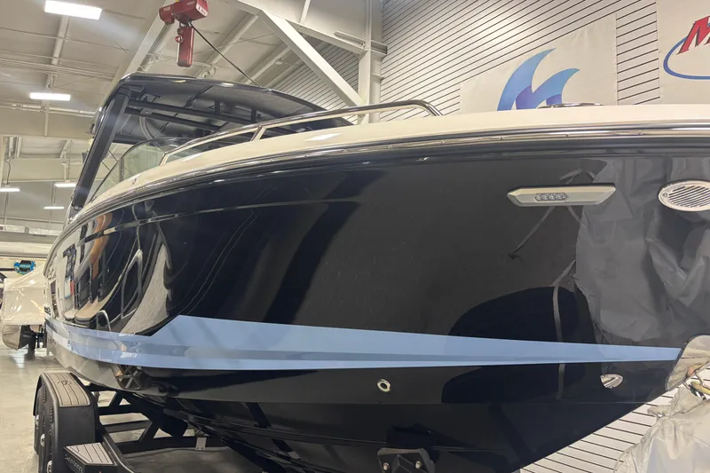 Slide: The Image of 2026 Chaparral SSX 30 boat in showroom, sleek black design with blue accent stripe. - 17