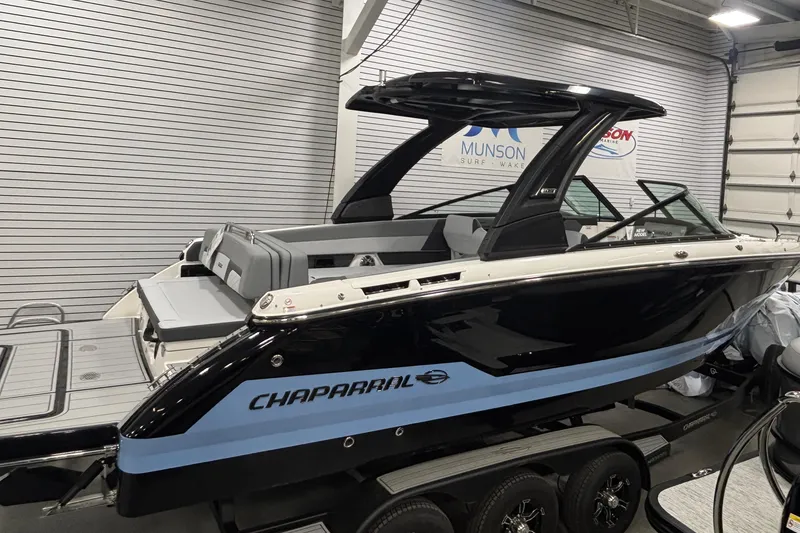 Slide: The Image of 2026 Chaparral SSX 30 boat in showroom, black and blue design, on trailer. - 2