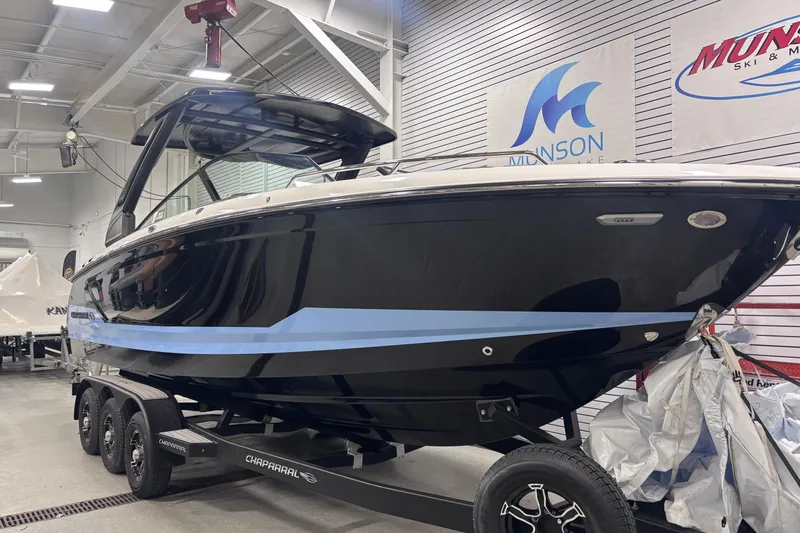Slide: The Image of 2026 Chaparral SSX 30 boat on trailer in showroom, sleek black design. - 6