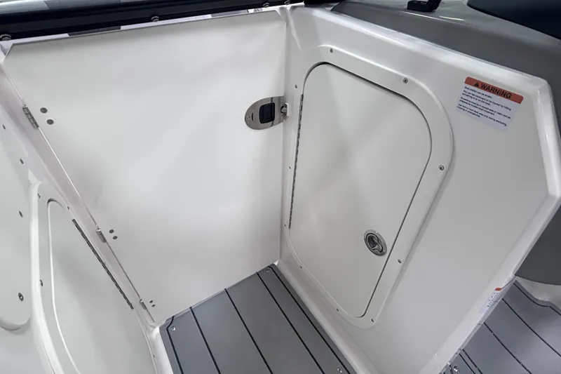 Slide: The Image of 2026 Chaparral 23 SSi boat interior with storage compartment and warning label. - 26