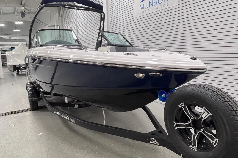 Slide: The Image of 2026 Chaparral 23 SSi boat on trailer in showroom, sleek design, black and white exterior. - 9