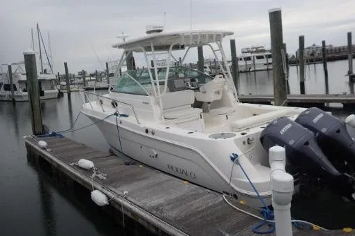 Slide: The Image of 2015 Robalo R305 Walkaround boat docked with twin engines, overcast sky. - 14
