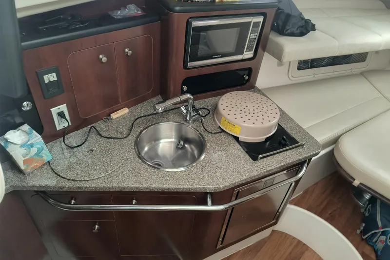 Slide: The Image of 2015 Robalo R305 Walkaround boat interior with kitchenette, sink, and microwave. - 17