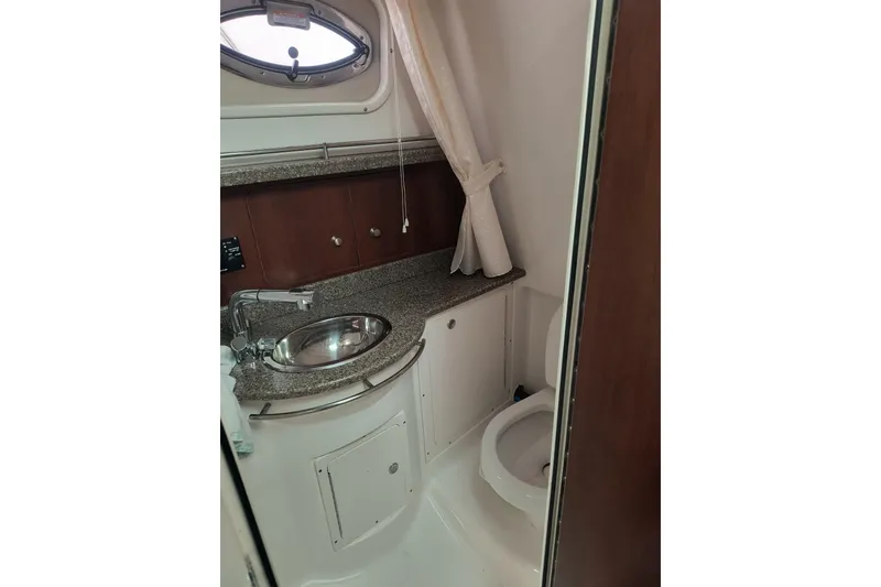 Slide: The Image of 2015 Robalo R305 Walkaround boat bathroom with sink, toilet, and porthole window. - 20