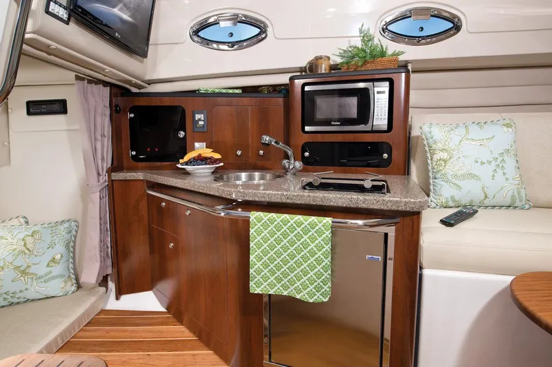 Slide: The Image of Manufacturer Provided Image: 2015 Robalo R305 Walkaround boat interior kitchen with microwave, sink, and seating area. - 9