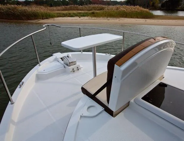 Slide: The Image of Manufacturer Provided Image: 2025 Ranger Tugs R-31 CB boat deck with seating and table, near a sandy shore. - 10