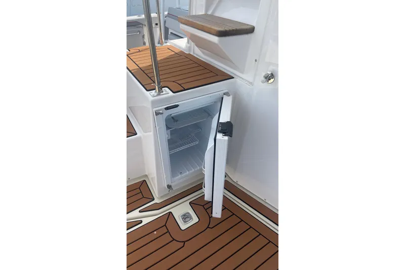 Slide: The Image of Open mini fridge on 2025 Ranger Tugs R-31 CB boat with teak flooring. - 12