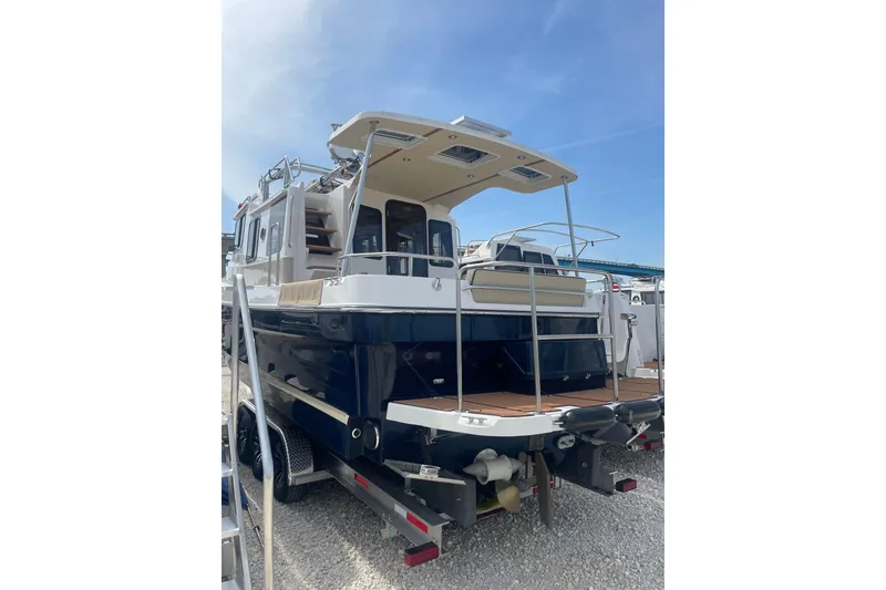 Slide: The Image of 2025 Ranger Tugs R-31 CB boat, rear view, docked on a trailer under clear blue sky. - 2