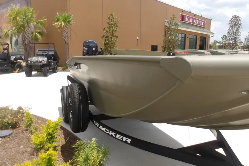Slide: The Image of 2026 Tracker Grizzly 1650 T Prairie Wings Edition boat on trailer outside service center. - 3
