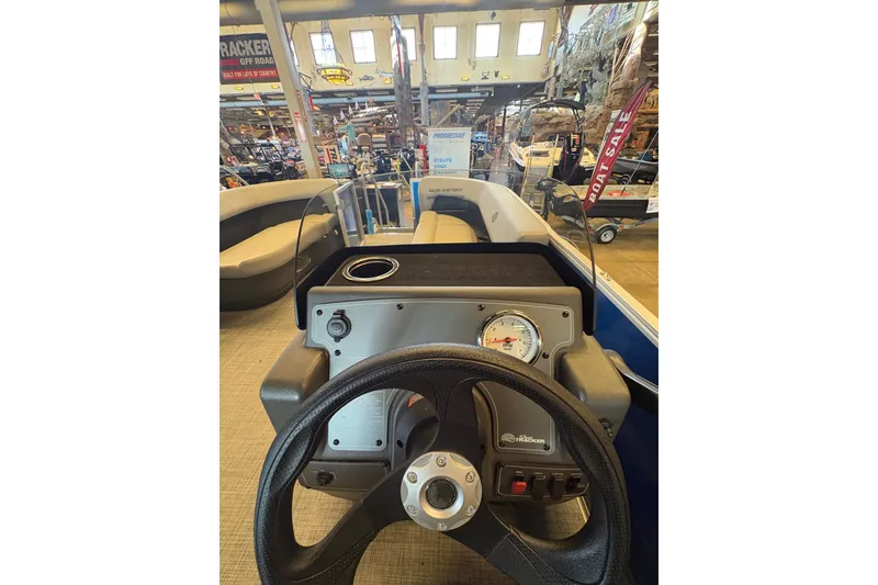 Slide: The Image of 2026 Sun Tracker Party Barge 16 DLX dashboard with steering wheel and gauge in showroom. - 74