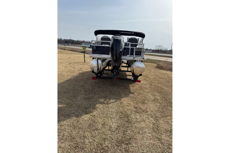 Slide: The Image of 2026 Sun Tracker Bass Buggy 18 DLX pontoon boat on grassy area, rear view. - 10