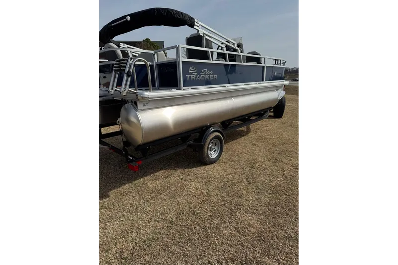 Slide: The Image of 2026 Sun Tracker Bass Buggy 18 DLX pontoon boat on trailer, parked on grass. - 9