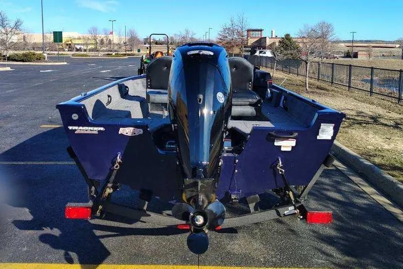 Slide: The Image of 2026 Tracker Pro Guide V-16 SC boat with outboard motor in parking lot. - 2