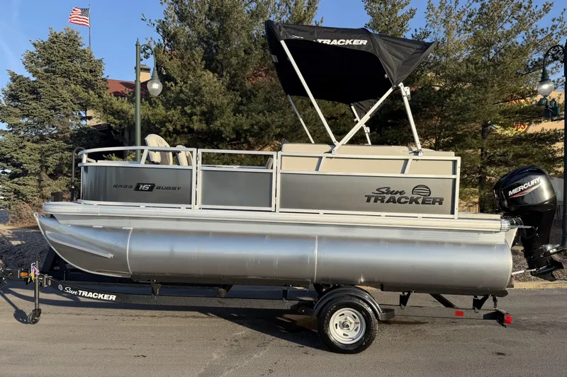 The Image of 2026 Sun Tracker Bass Buggy 16 XL Select pontoon boat on trailer, outdoor setting. - 0