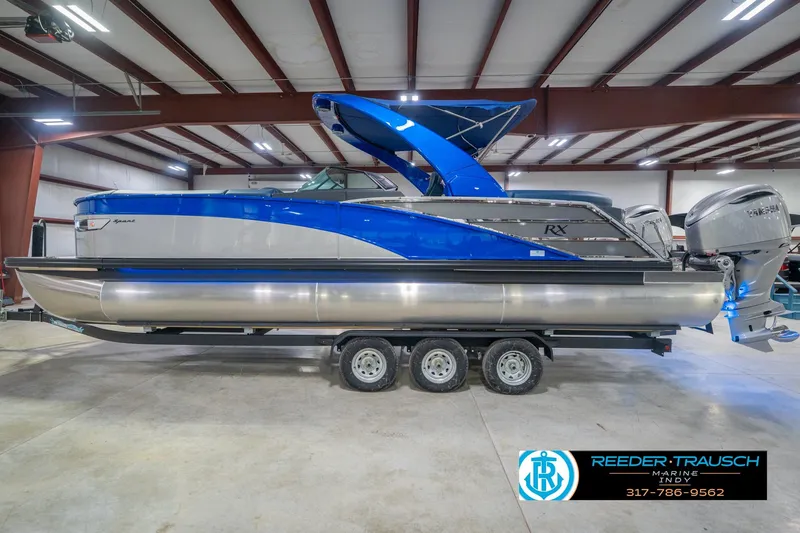 Slide: The Image of 2026 Bennington 27 RX pontoon boat with blue accents in a showroom. - 10