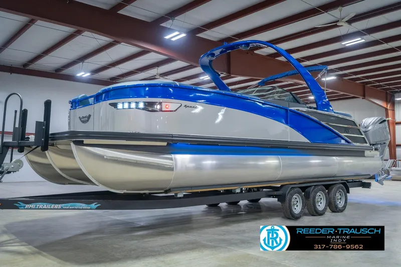 Slide: The Image of 2026 Bennington 27 RX pontoon boat in showroom, blue and silver design, on trailer. - 2