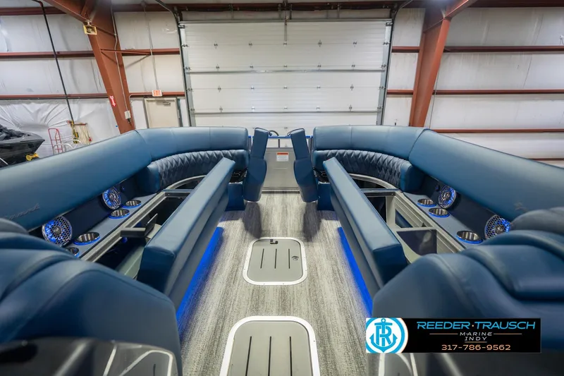 Slide: The Image of 2026 Bennington 27 RX boat interior with blue seating and cup holders in a garage. - 21