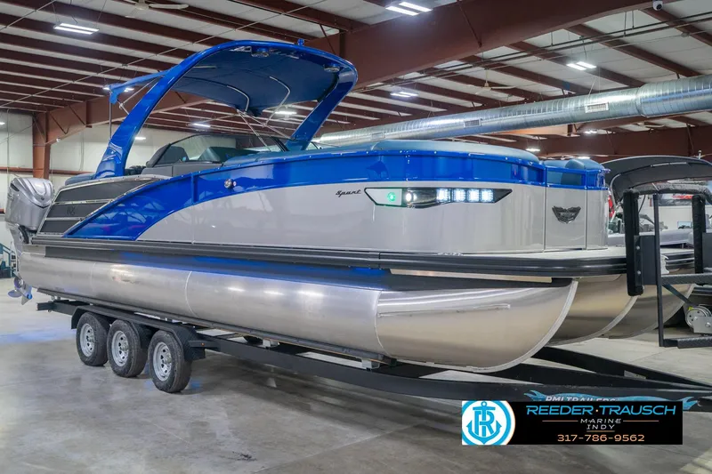 Slide: The Image of 2026 Bennington 27 RX pontoon boat in showroom, featuring sleek blue and silver design. - 5