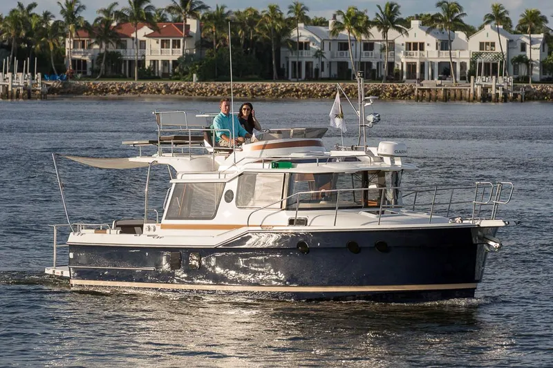 Slide: The Image of Manufacturer Provided Image: 2025 Ranger Tugs R-29 CB cruising on a scenic waterfront with palm trees and houses. - 3