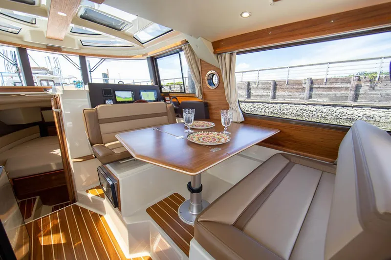 Slide: The Image of Manufacturer Provided Image: Interior of 2025 Ranger Tugs R-29 CB, featuring a cozy dining area with elegant wood finishes. - 7