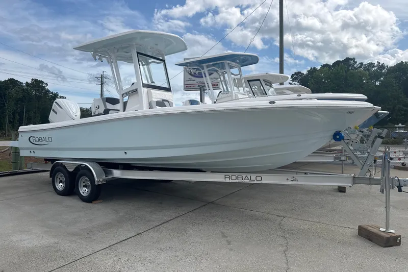 Slide: The Image of 2026 Robalo 246 Cayman boat on trailer, displayed outdoors under a cloudy sky. - 2