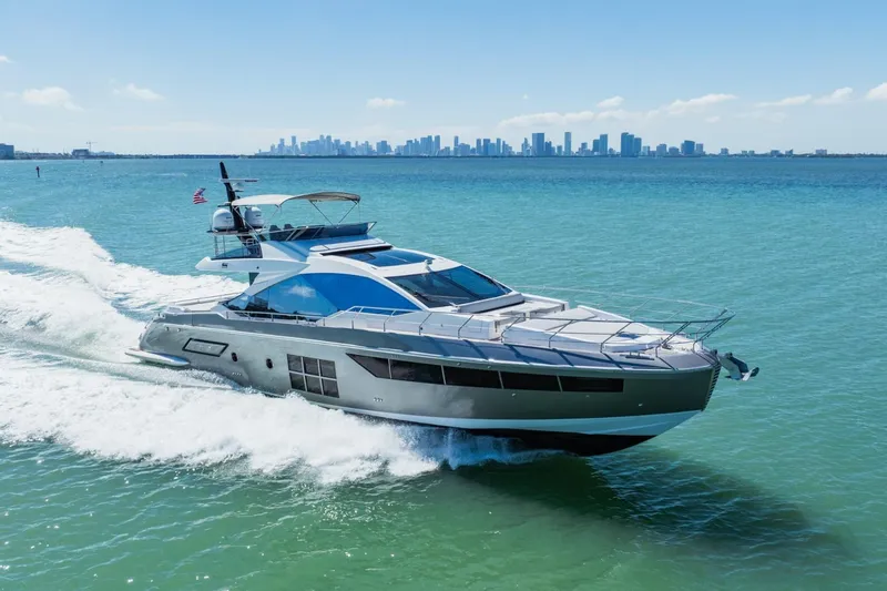 Slide: The Image of 2019 Azimut S7 yacht cruising on turquoise waters with city skyline in background. - 1