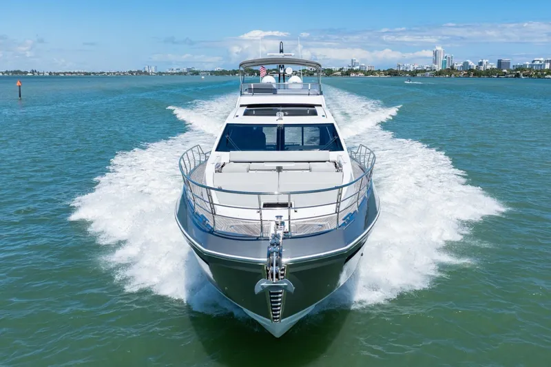 Slide: The Image of 2019 Azimut S7 yacht cruising on open water, city skyline in background. - 2