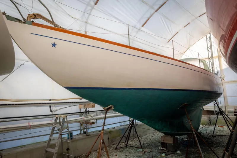Slide: The Image of 1965 Concordia 39 sailboat in dry dock, white and green hull, under a protective cover. - 11