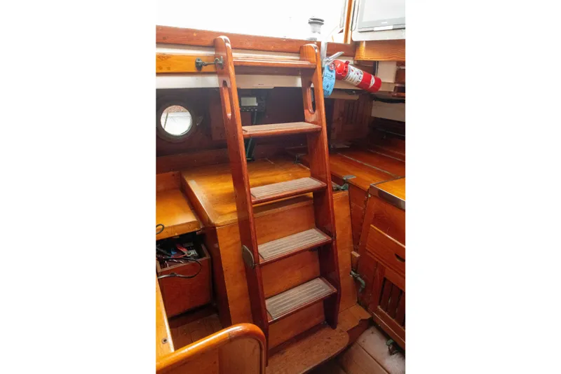 Slide: The Image of Wooden interior stairs on a 1965 Concordia 39 sailboat, featuring a fire extinguisher. - 27