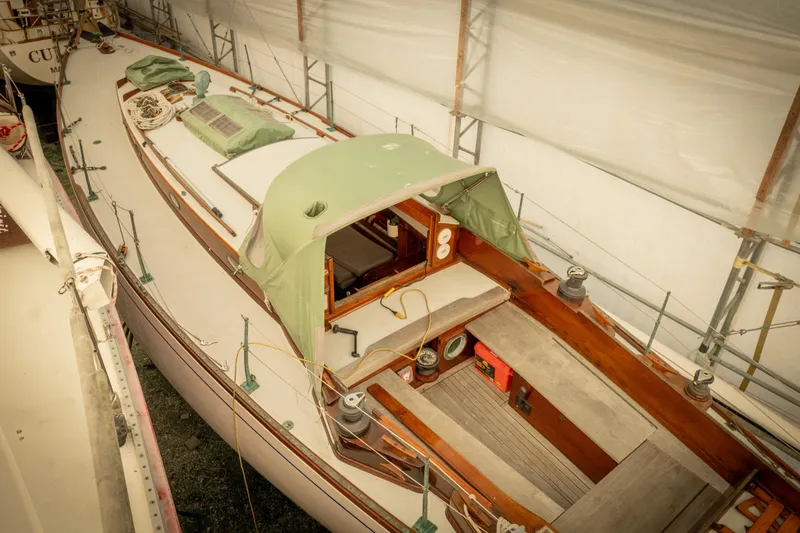 Slide: The Image of 1965 Concordia 39 sailboat in storage, featuring a green canopy and wooden deck. - 9