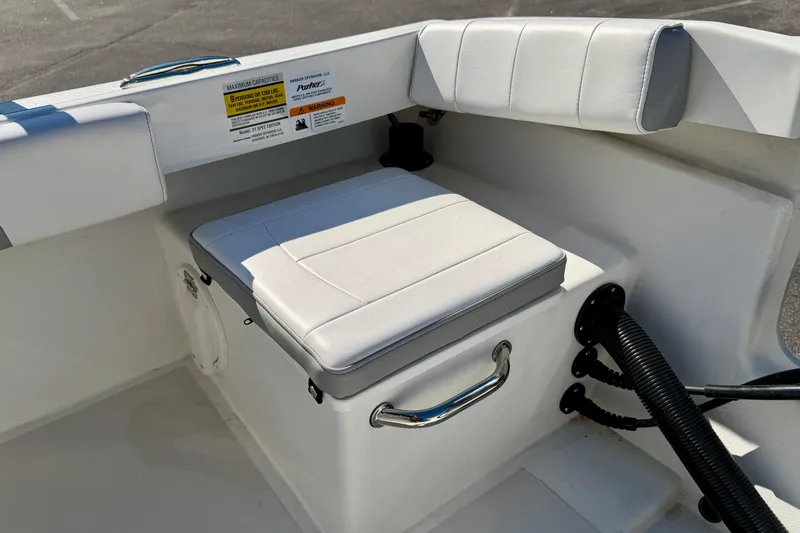 Slide: The Image of 2024 Parker 2100 Special Edition boat interior with cushioned seating and safety labels. - 19