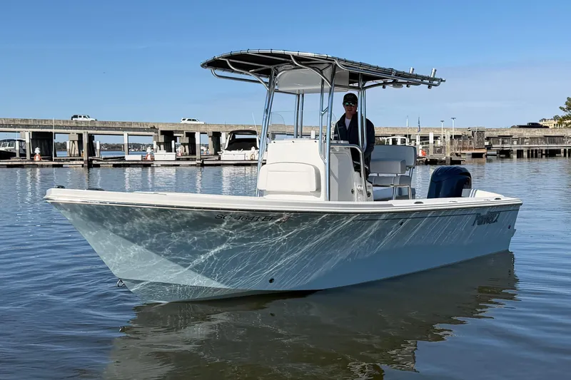 Slide: The Image of 2024 Parker 2100 Special Edition boat on calm water near a marina. - 2