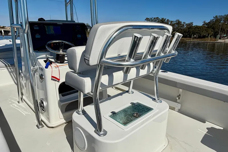 Slide: The Image of 2024 Parker 2100 Special Edition boat interior with helm and seating, on calm water. - 24