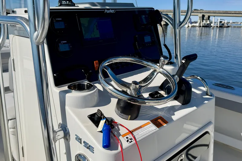 Slide: The Image of 2024 Parker 2100 Special Edition boat console with steering wheel and controls, dockside view. - 27